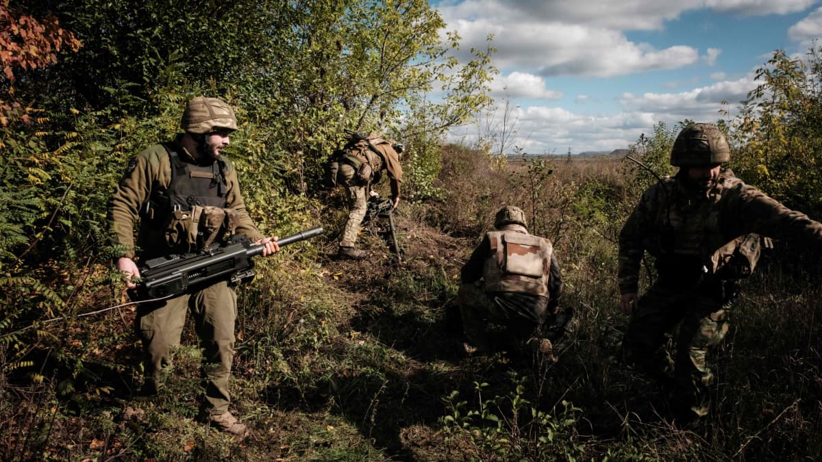Sotilaat kantavat aseita metsikössä.
