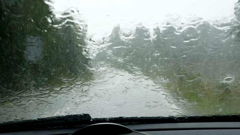 A picture of the inside of a car with a windshield that is gathering a lot of water.