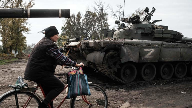 Henkilö pyöräilee hylätyn tankin ohitse.