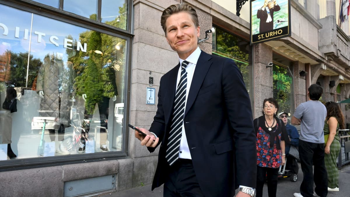 Antti Häkkänen kävelee Ostrobotnian edessä kadulla puhelin kädessään.