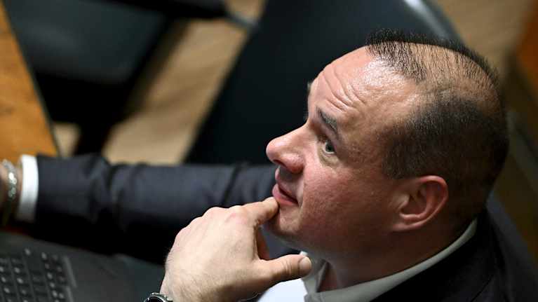 Mikko Polvinen istuu eduskunnan istuntosalissa.