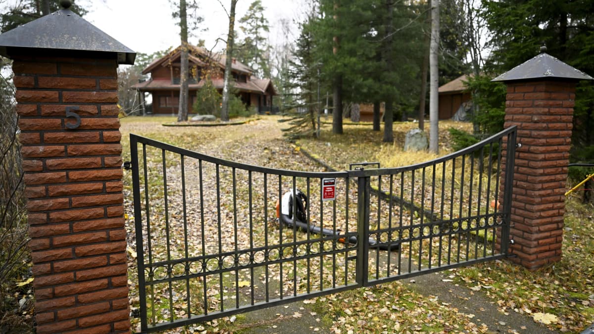 Suljettu portti talon edustalla. Portin takana on lehtipuhallin maassa.