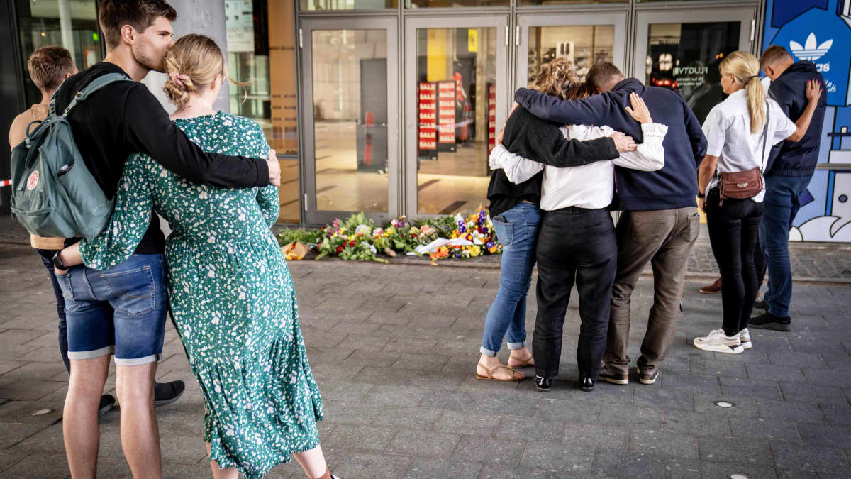 Ihmiset halaavat toisaan lasiovien edustalla.