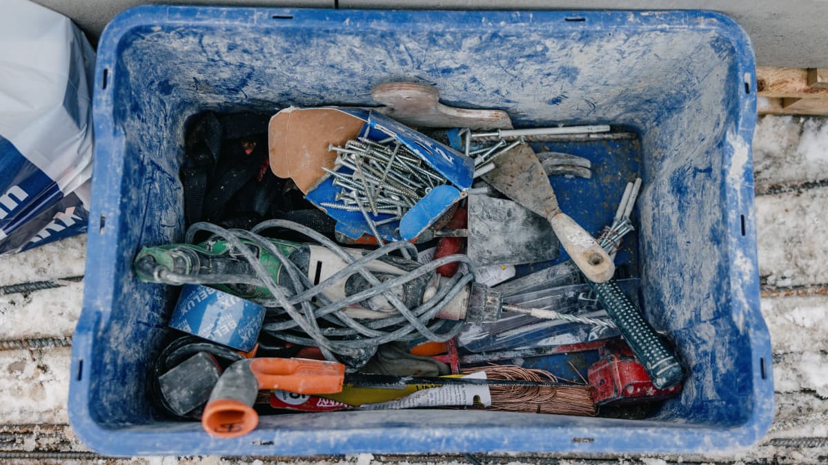 Työkaluja sinisessä muovilaatikossa pientalon rakennustyömaalla.