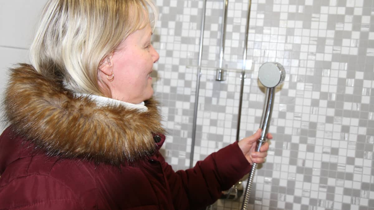 Asunto Oy Kangaskirsin  hallituksen puheenjohtaja Piia Rosilainen esittelee taloyhtiön saunan uusia vesikalusteita.
