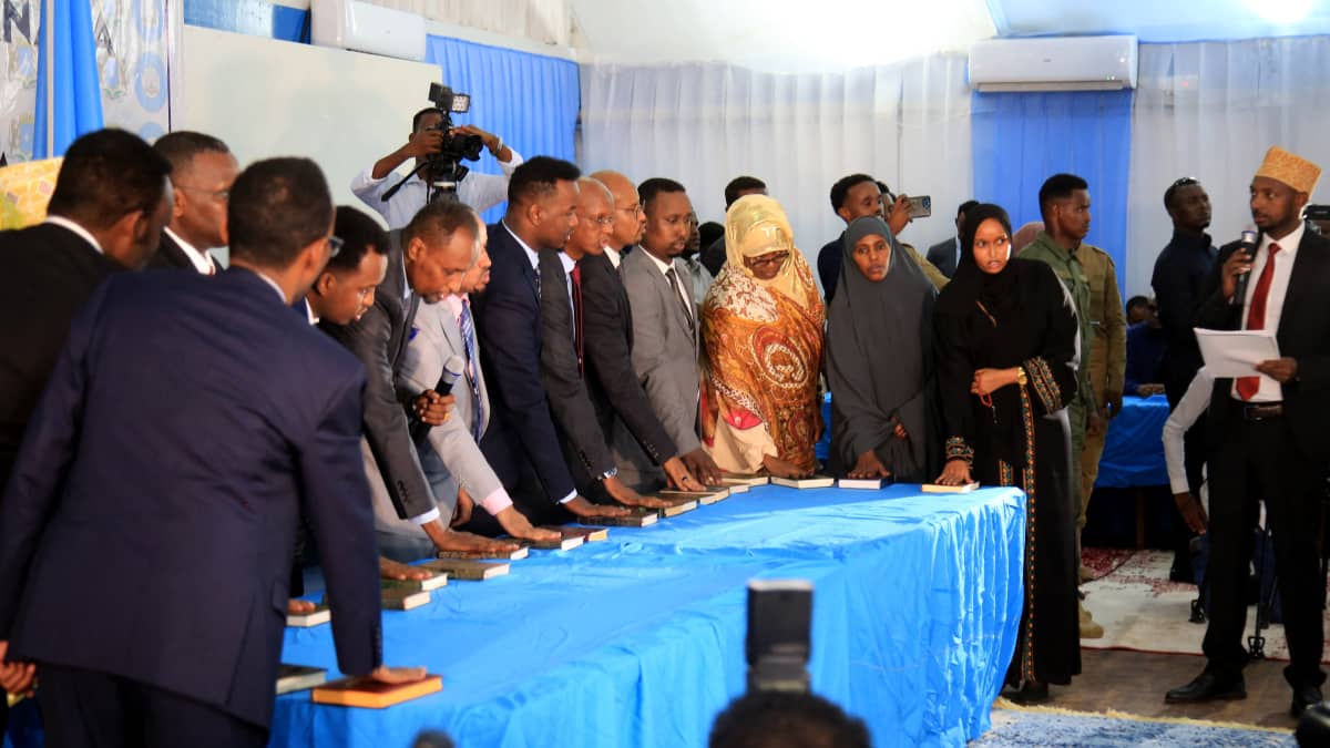 Somalialaisia mies- ja naiskansanedustajia vannomassa virkavalaansa sinisen pöydän takana suuressa teltassa. 
