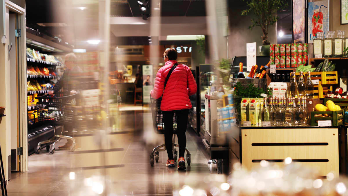 Kaksi ihmistä kulkee ruokakaupassa ostoskärryjen kanssa.