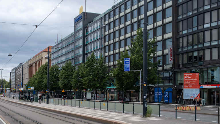 Tram stop platform in the Hakaniemi district of Helsinki with buildings in the background.