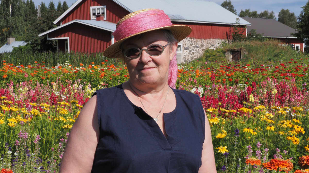 Kuvassa on nainen, joka on peltojen keskellä. 