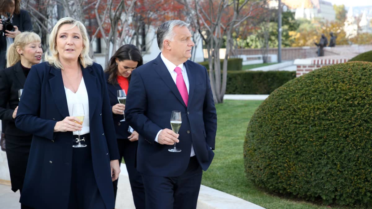 Marine Le Pen ja Viktor Orban kävelemässä rinnakkain viinilasi kädessä.
