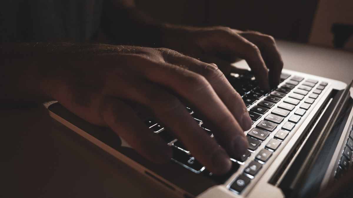 Miehen kädet kannettavalla tietokoneella.