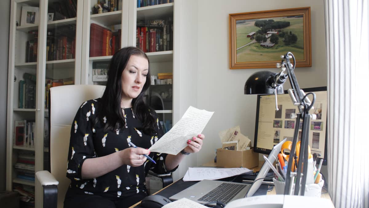 Sukututkimusta harrastava Anu Järvinen istuu työpöytänsä äärellä.