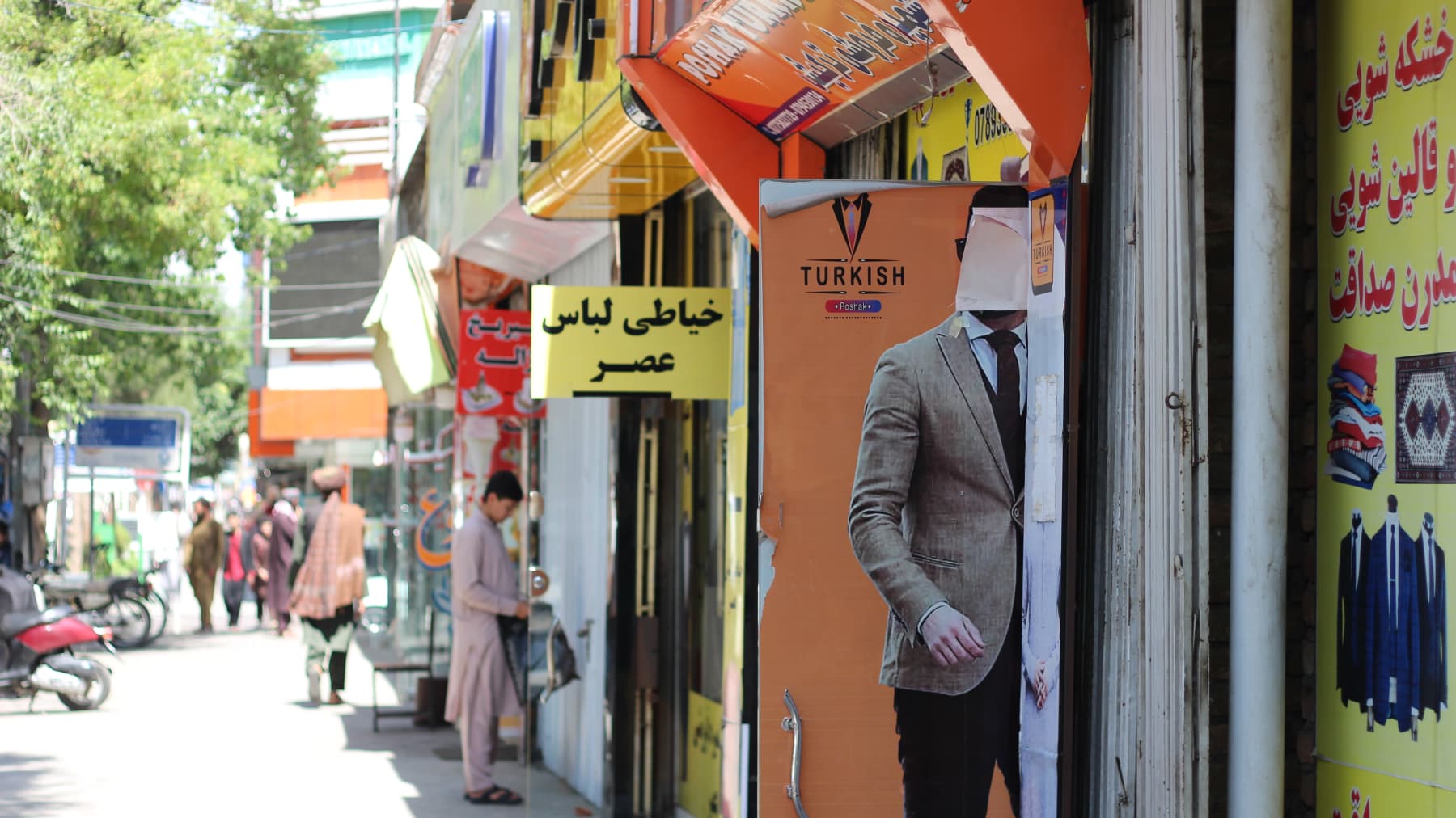 Kabulissa vaatteita myyvän kaupan ovessa on miehen kuva.