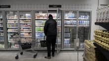 Asiakas kylmäkaapin vieressä ruokakaupassa.