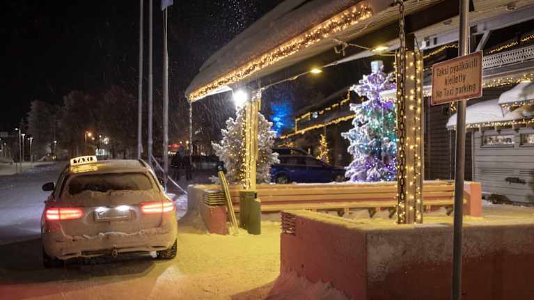 A taxi parked in front of a no-parking sign.