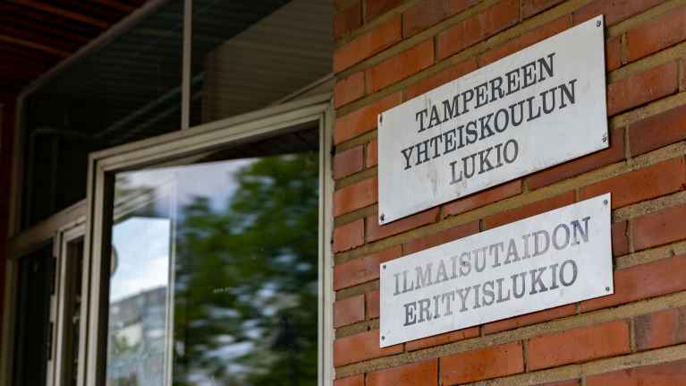 Tampereen yhteiskoulun lukion kyltti rakennuksen seinässä.