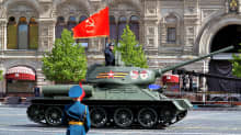 Panssarivaunu ajaa Punaisella torilla. Tornissa seisoo sotilas käsi lipassa. Etualalla on sotilas sinisessä paraatiunivormussa. Panssarivaunussa on punalippu, johon on kuvattu sirppi ja vasara. Taustalla näkyy GUM-tavaratalo.