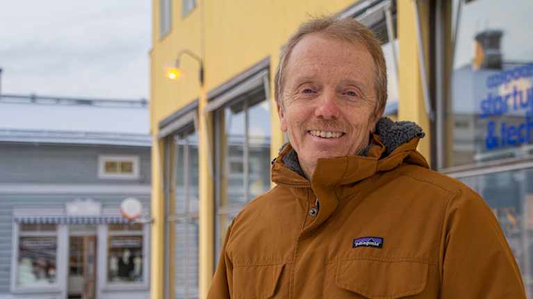 En man står utomhus och tittar in i kameran.