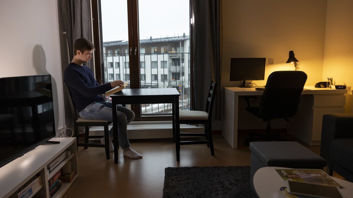opiskelija Mikko Vanhala lukee oppikirjaa ikkunan edessä vuokrayksiössään.