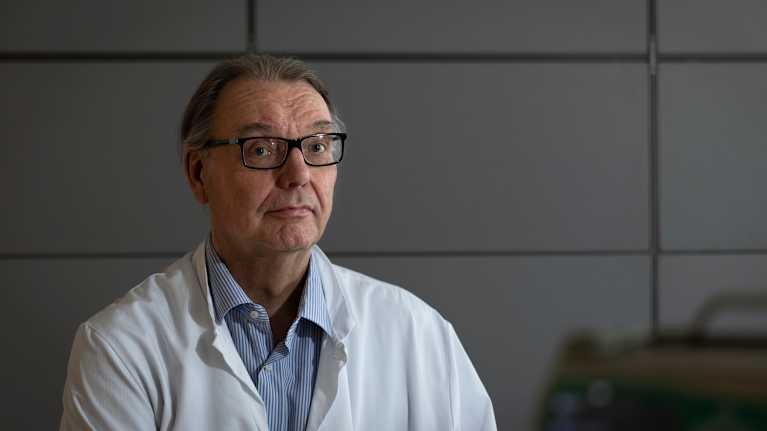 A male doctor looks towards in half-length.