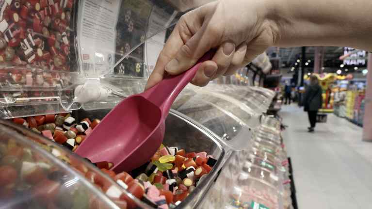 A hand scooping candy from a bin. 