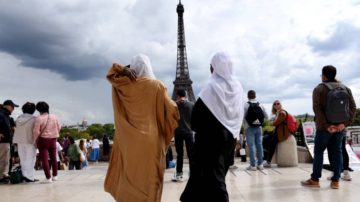 Kaksi Abaijoihin pukeutunutta naista aukiolla. Taustalla näkyy Eiffel-torni.