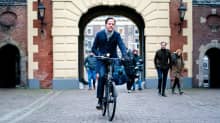 Mark Rutte ajaa polkupyörällä omena kädessään.