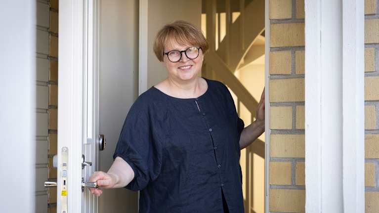 Olga Filipova hymyilee asuntonsa ulko-ovella.