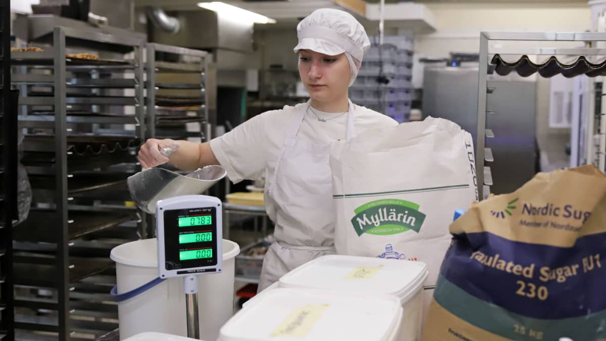 Emilia Honkanen mittaa jauhoja astiaan leipomossa.