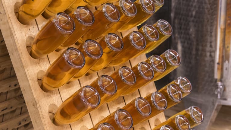 Kirkaslasisia omenakuohuviinipulloja puisessa pystysäilytystelineessä.