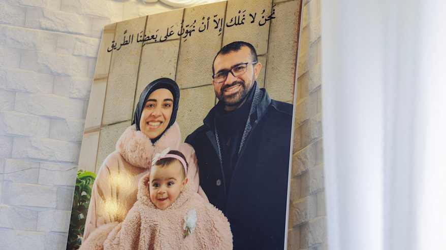 Seinätaulussa hymyilee perhe, johon kuuluu huivipäinen musliminainen, mies ja pieni tyttö.