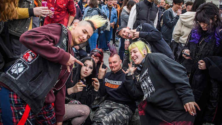 Joukko punkkareita poseeraa kameralle ihmisjoukossa yleisötapahtumassa.