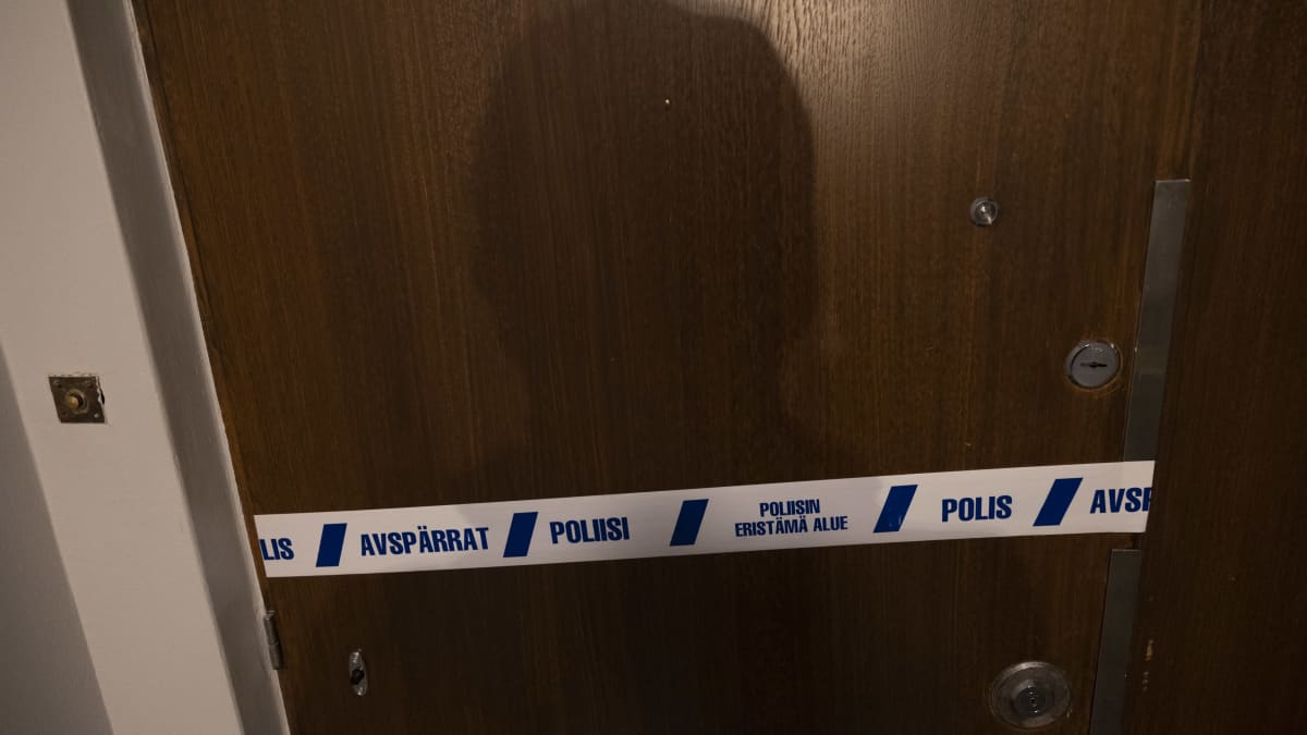 Poliisin eristämä alue teippaus kerrostalon ovessa.