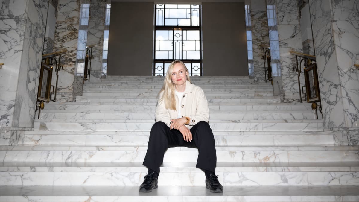 Maria Ohisalo istuu Eduskuntatalon marmoriportailla ja katsoo kameraan.