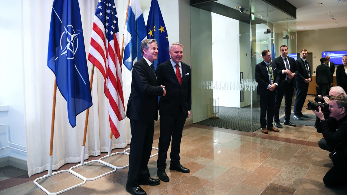 Antony Blinken ja Pekka Haavisto kättelevät. Taustalla Naton, Yhdysvaltojen, Suomen ja EU:n liput.