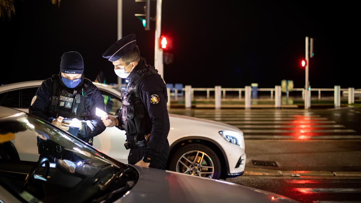 Poliisit tarkistavat autoilijan papereita pimeällä.