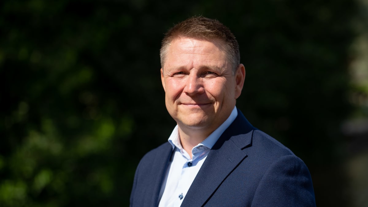 Juha Jokela seisoo puku päällä katsoo kameraan.