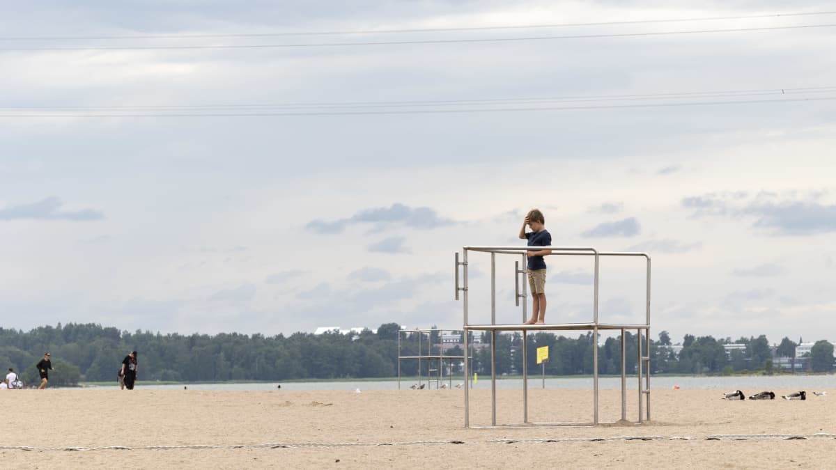 A child stands on climbing equipment. 
