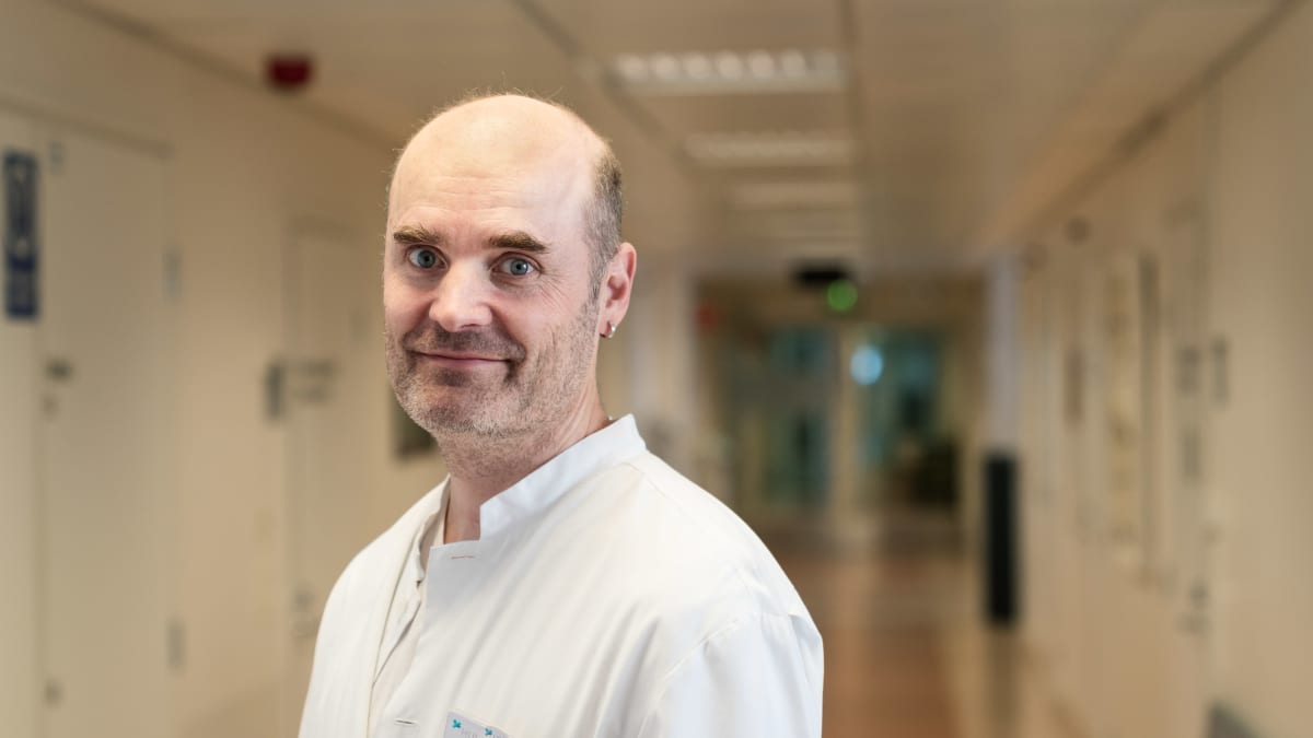 Perinnöllisyyslääkäri Kirmo Wartivaara hymyilee valkeassa takissaan naistenklinikan käytävällä 18.9.2019.