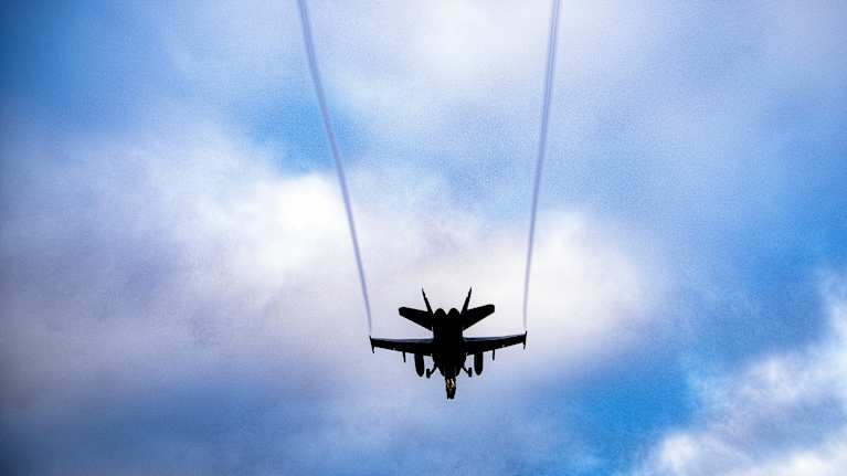 Suomen Ilmavoimien F/A-18 Hornet lentää sinistä taivasta vasten jättäen peräänsä kaksi vanaa.