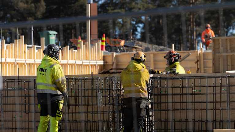 Rakennusmiehet katsovat Harjun rakennustyömaata Jyväskylässä. Yhden miehen selässä lukee Bolt.