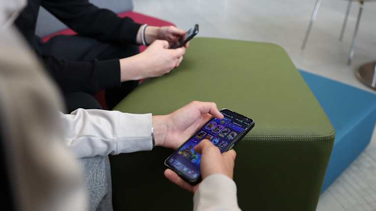 kahdet kädet pitelevät matkapuhelimia, joissa on avattuna pelisovellukset.