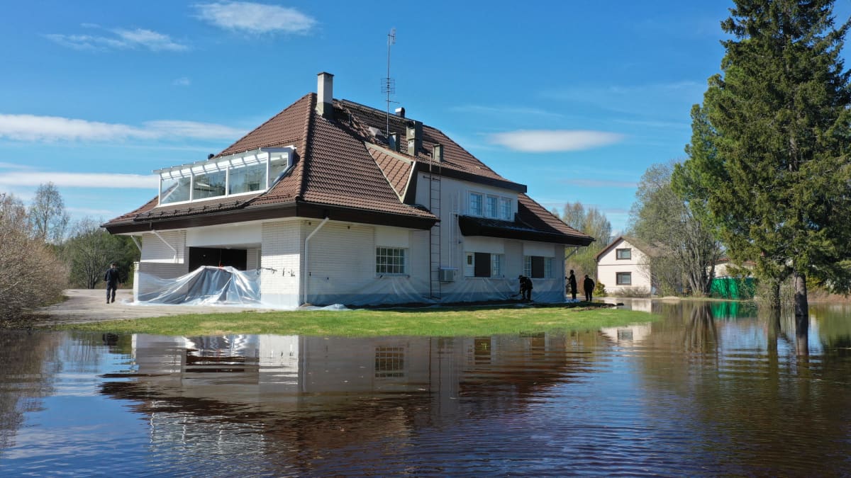 Valkoinen talo, tulvavesi noussut pihalle. 