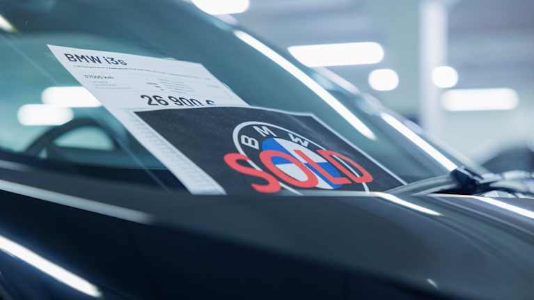There is a sign on the windshield of the dark car saying that it has been sold.