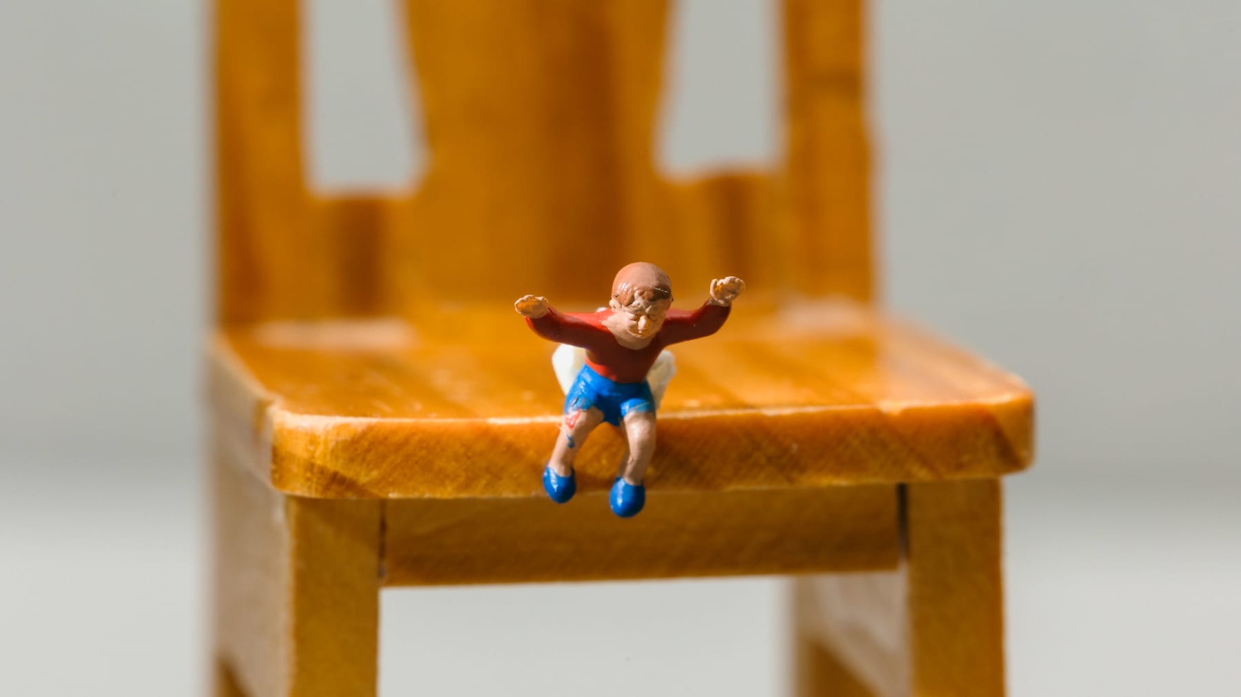 Miniatyyrihahmo on putoamaisillaan suurelta tuolilta.