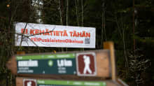 Takana Puskiaisten oikaisua vastustava banderolli ja etualalla Birgitan polun reitin opasteita.