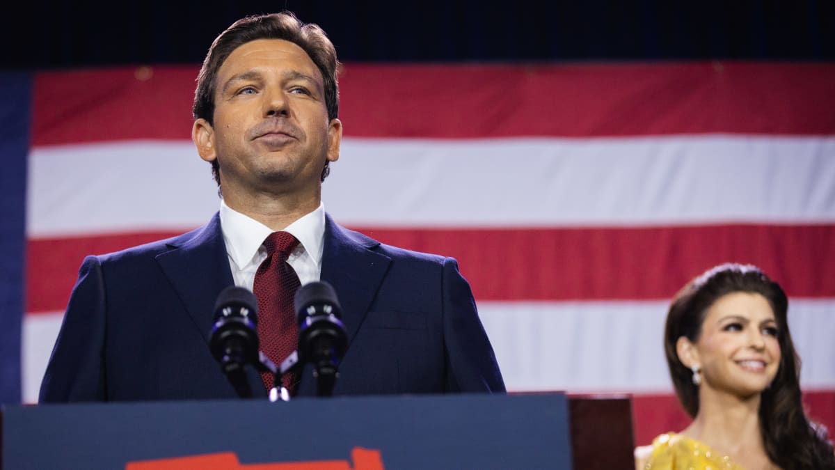 Etualalla Floridan kuvernööri Ron DeSantis puhujapöntössä, taustalla USA:n lippu ja puoliso Casey DeSantis.