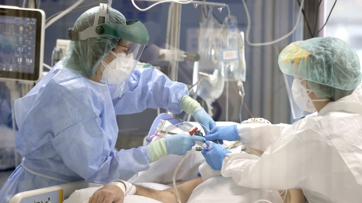 Suojapukuihin varustautuneet sairaanhoitajat hoitavat koronaviruspotilasta teho-osastolla.