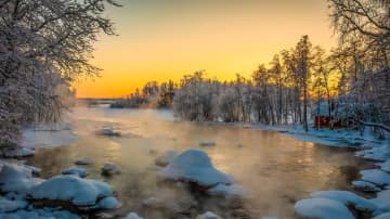 Kylmä päivä Varkaudessa. Joki höyryää, punainen mökki veden äärellä. 