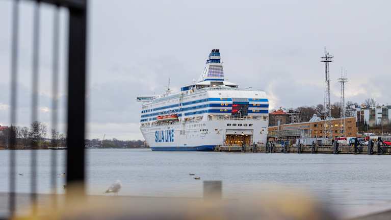 A large blue and white passenger ship awaits passengers in the harbor.